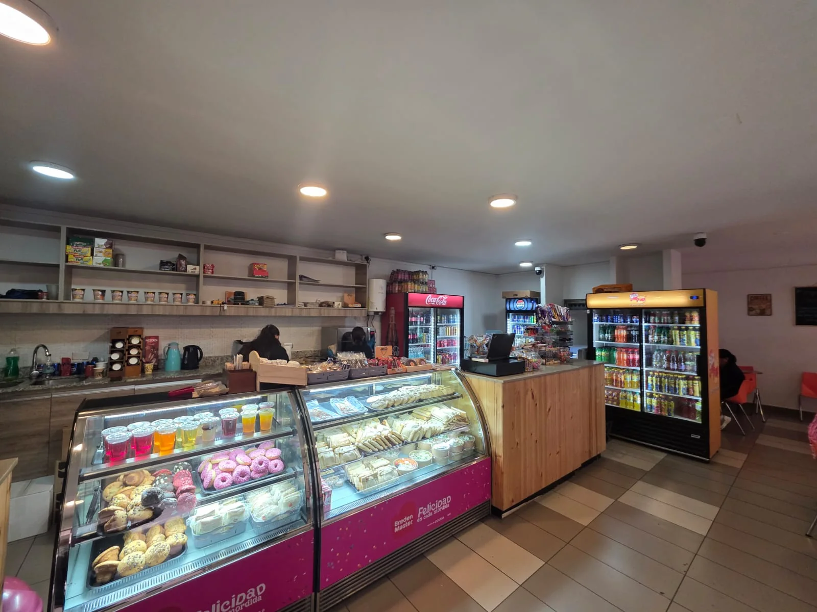 Cafetería Stop Café en el Patio Central de ENAC, con vitrinas de productos y refrigeradores de bebidas