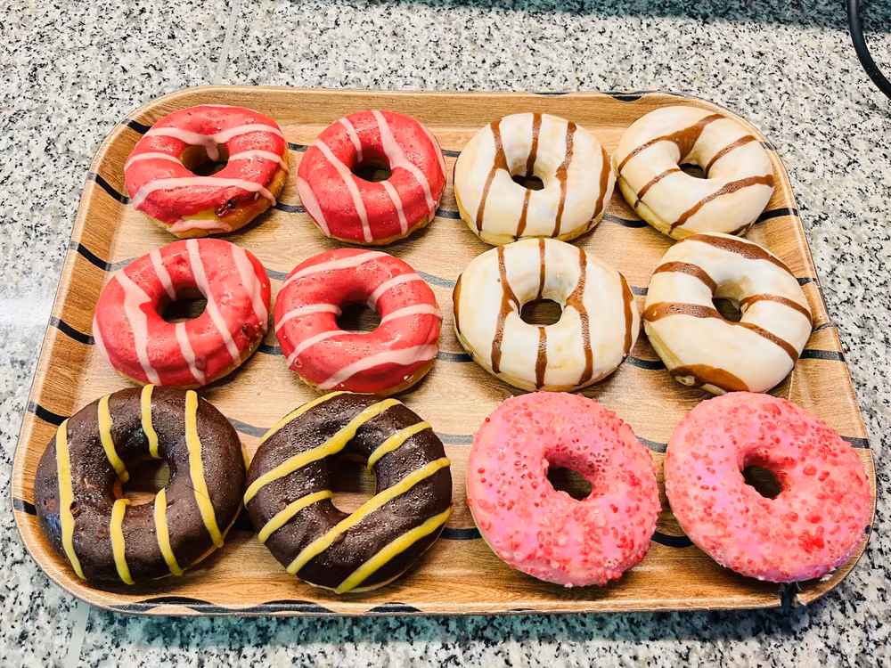Donuts glaseados y bañados en chocolate, recién surtidos sobre una tabla