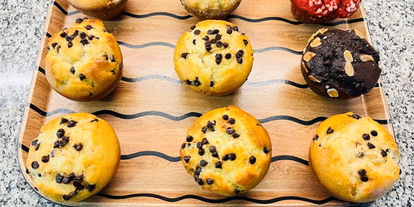 Muffins de vainilla, chips de chocolate y berries sobre tabla de madera.